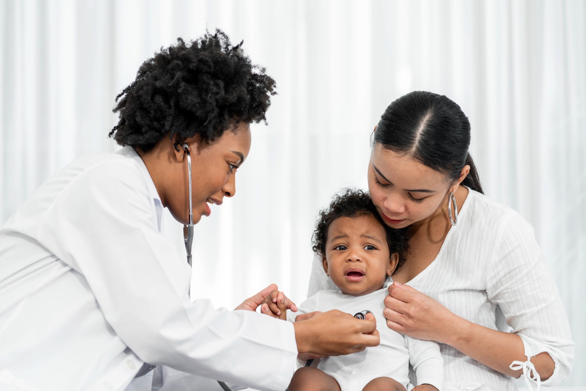 A clinician examining an infant with a parent present